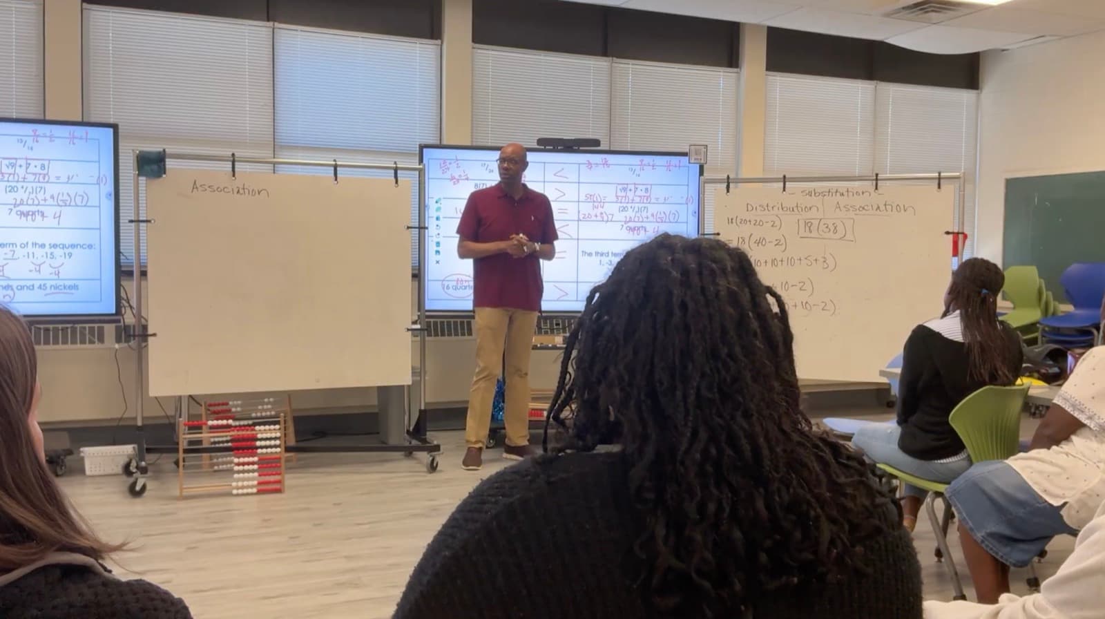 Kevin Moore facilitating for a room of seated teachers, with whiteboards behind him showing worked expressions headed Distribution and Association.